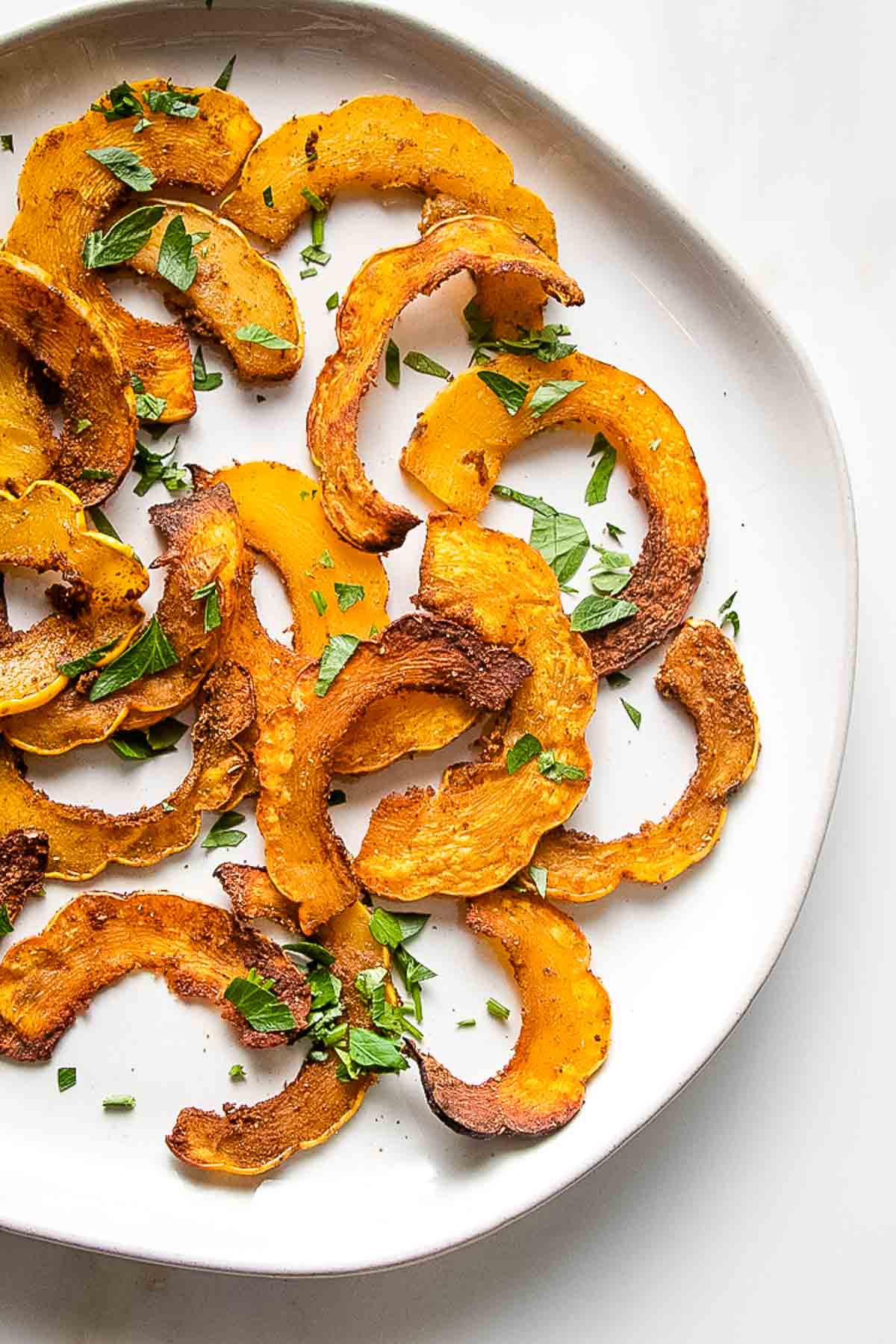 Roasted delicata squash in thin slices with spices and fresh herbs.