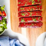 Meatloaf, with tomato sauce glaze, sprinkled with fresh herbs, cut into thick slices.