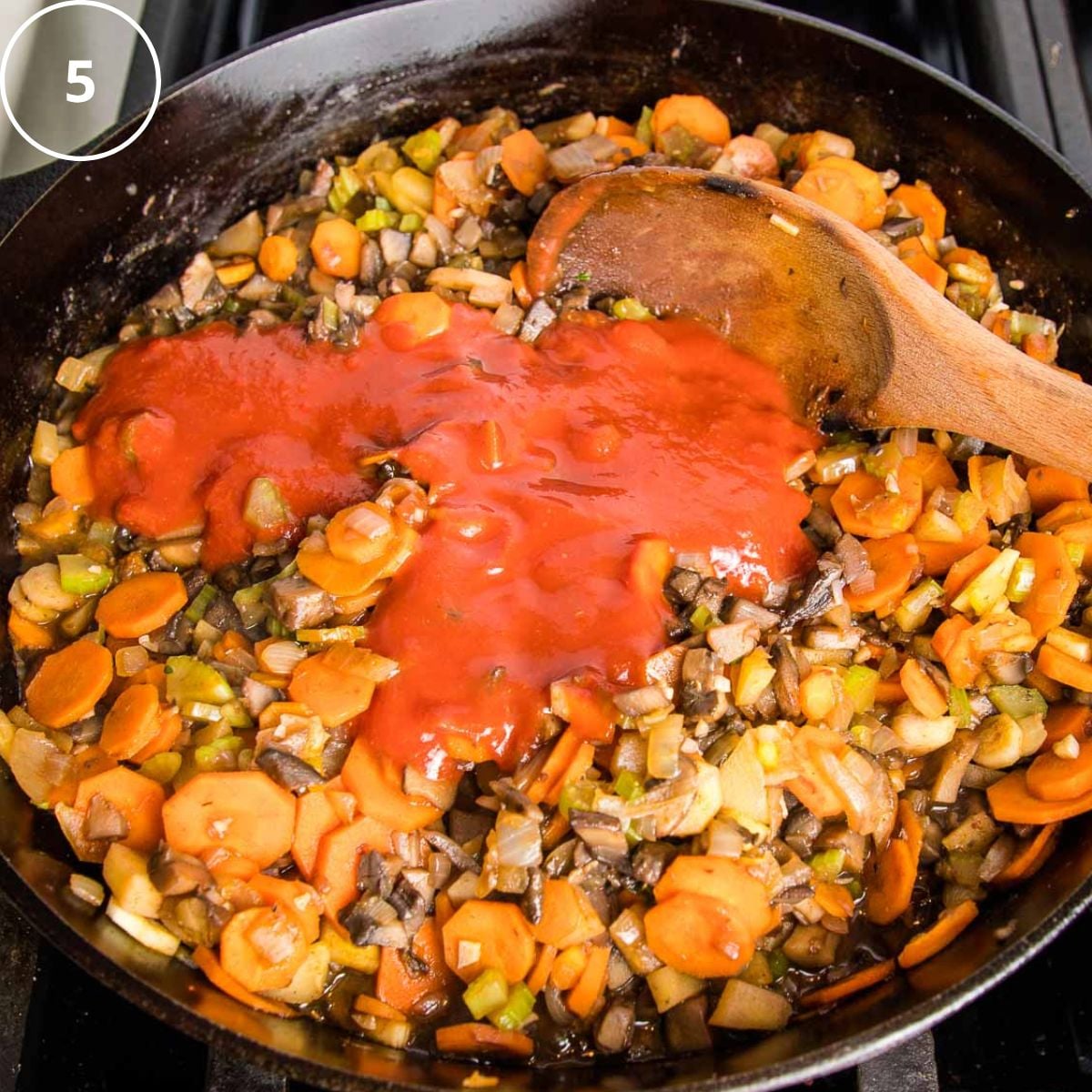 Sauteed veggies in a cast iron skillet with tomato sauce poured over the top.