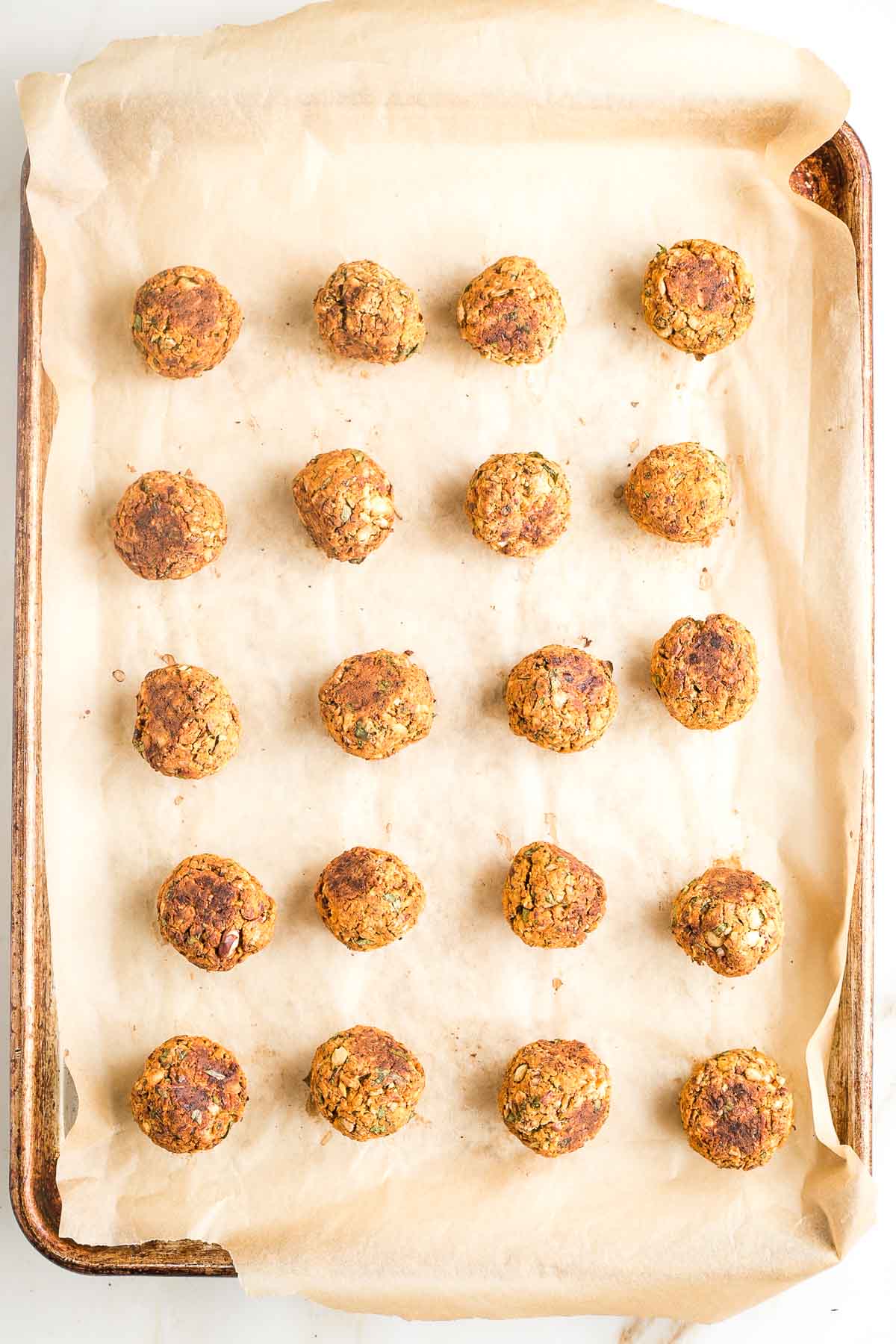 Baking tray with rows of cooked veggie balls.