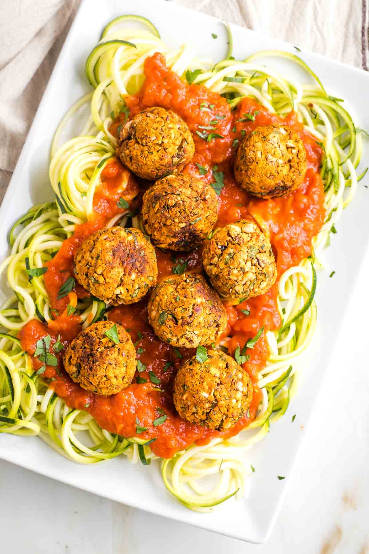 Platter filled with zucchini noodles, marinara and plant based meatballs.