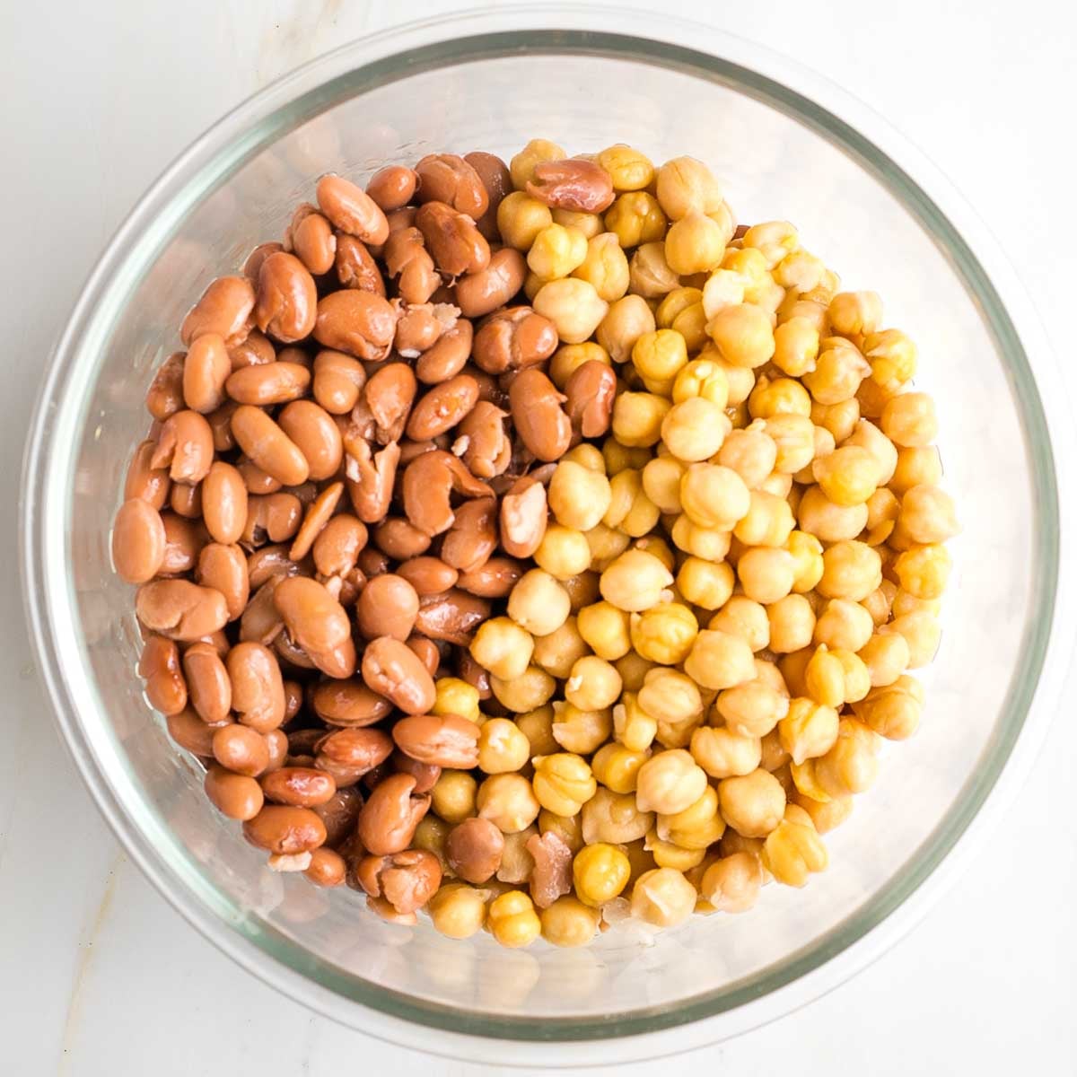 Pinto beans and chick peas in a glass mixing bowl.