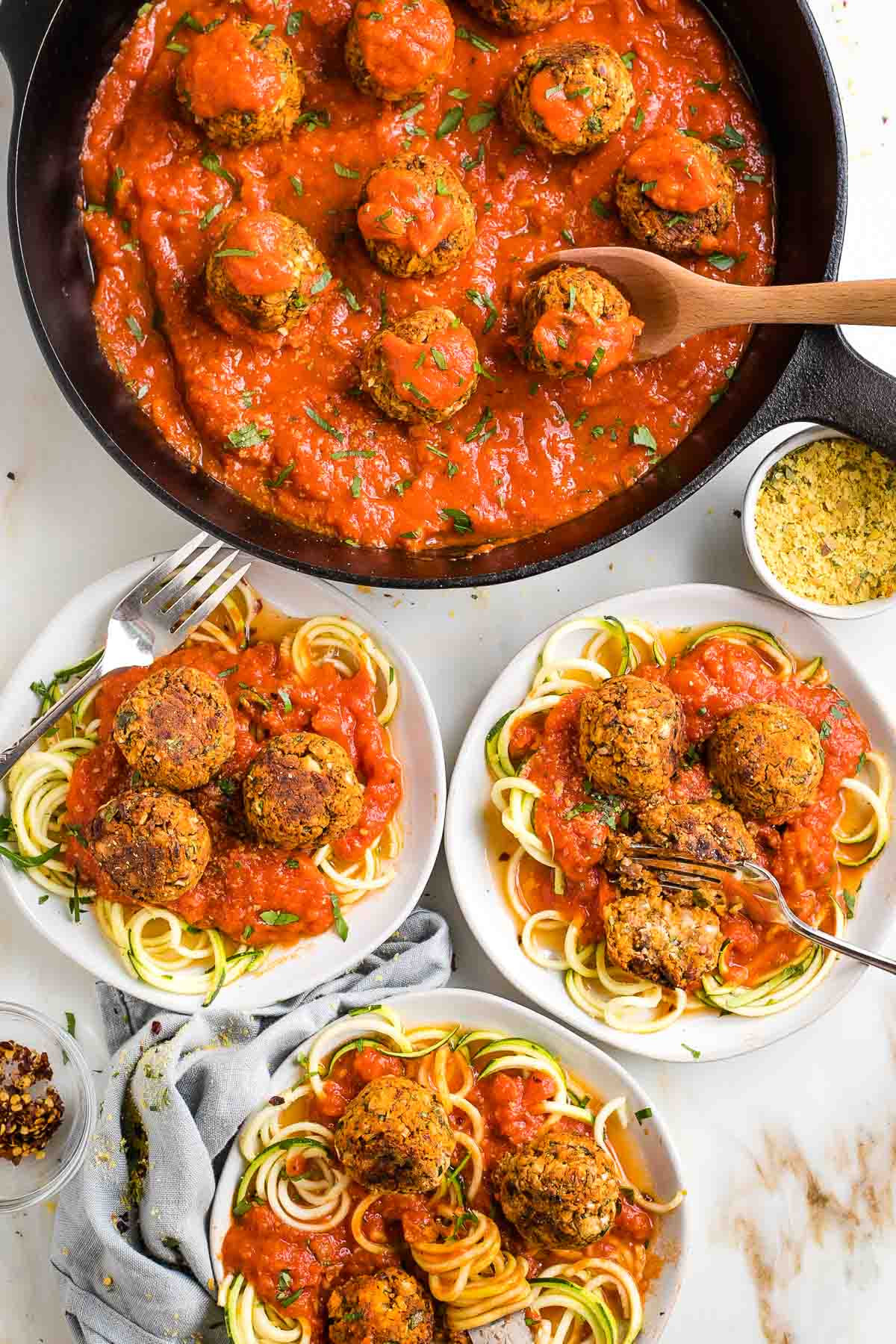 Vegan meatballs in tomato sauce, served on plates with zucchini noodles.