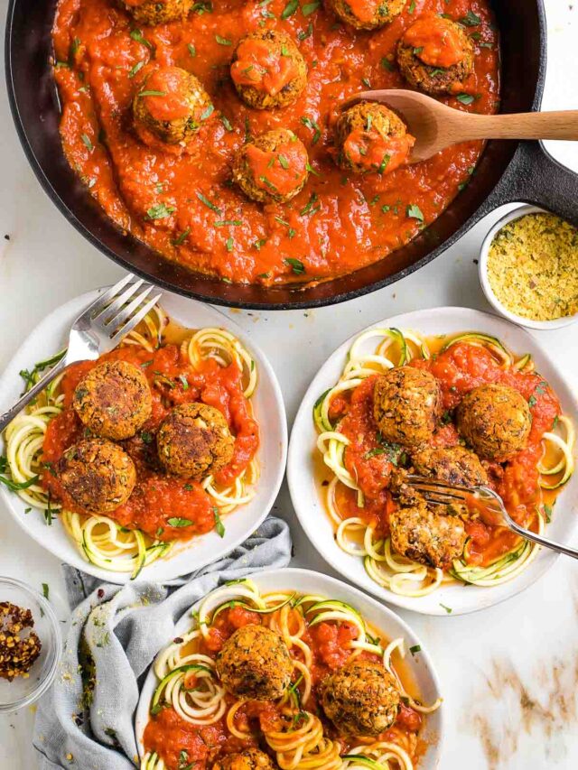 Vegan meatballs in tomato sauce, served on plates with zucchini noodles.