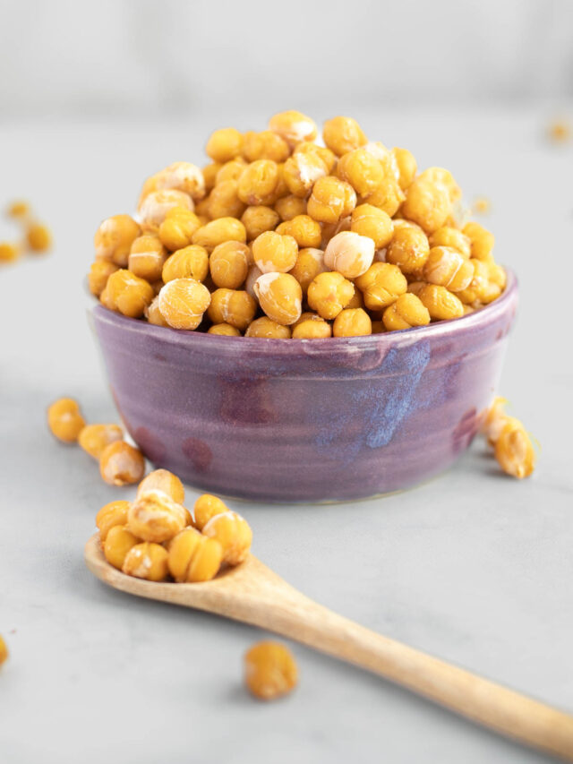 Crunchy roasted chickpeas in a purple bowl. A spoonful close up in front of the bowl.