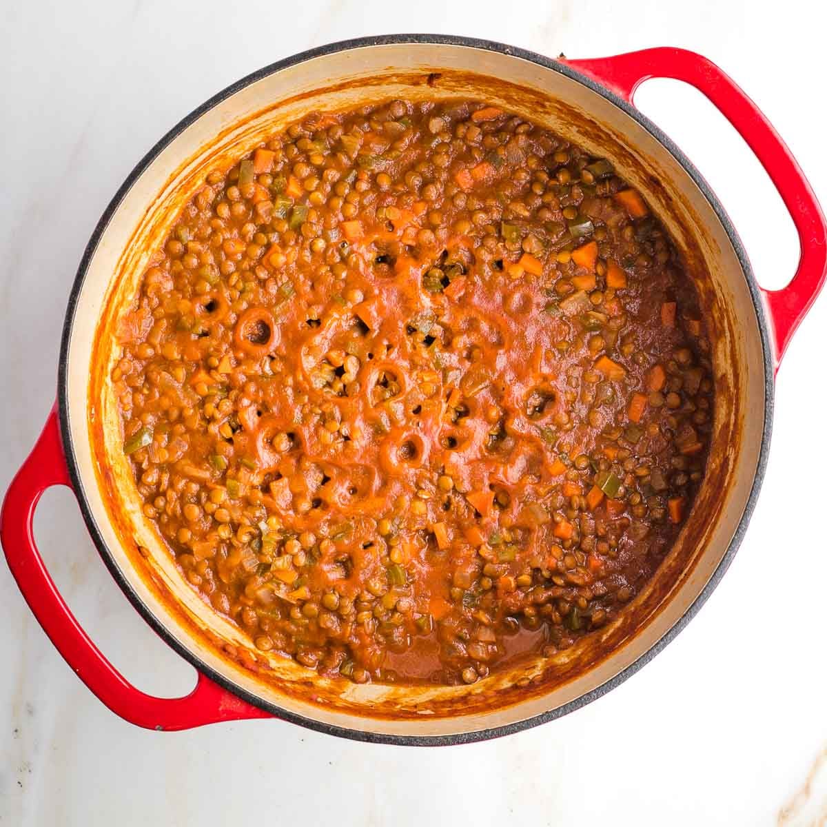 Dutch oven with vegan sloppy joes mixture, holes on top where the sauce evaporated.