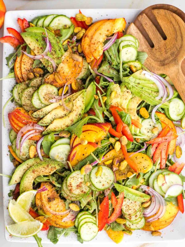 Sliced nectarines, avocados, cucumbers, red peppers and onions on a large platter.