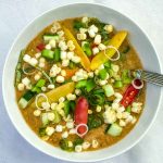 Chunks of vegetables floating on top of tomato gazpacho soup.