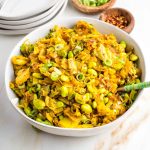 Bowl full of chopped cabbage with onions and edamame in a yellow curry, garnished with sliced scallions.