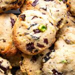 Pile of chocolate chunk cookies with pistachios and dried cherries.