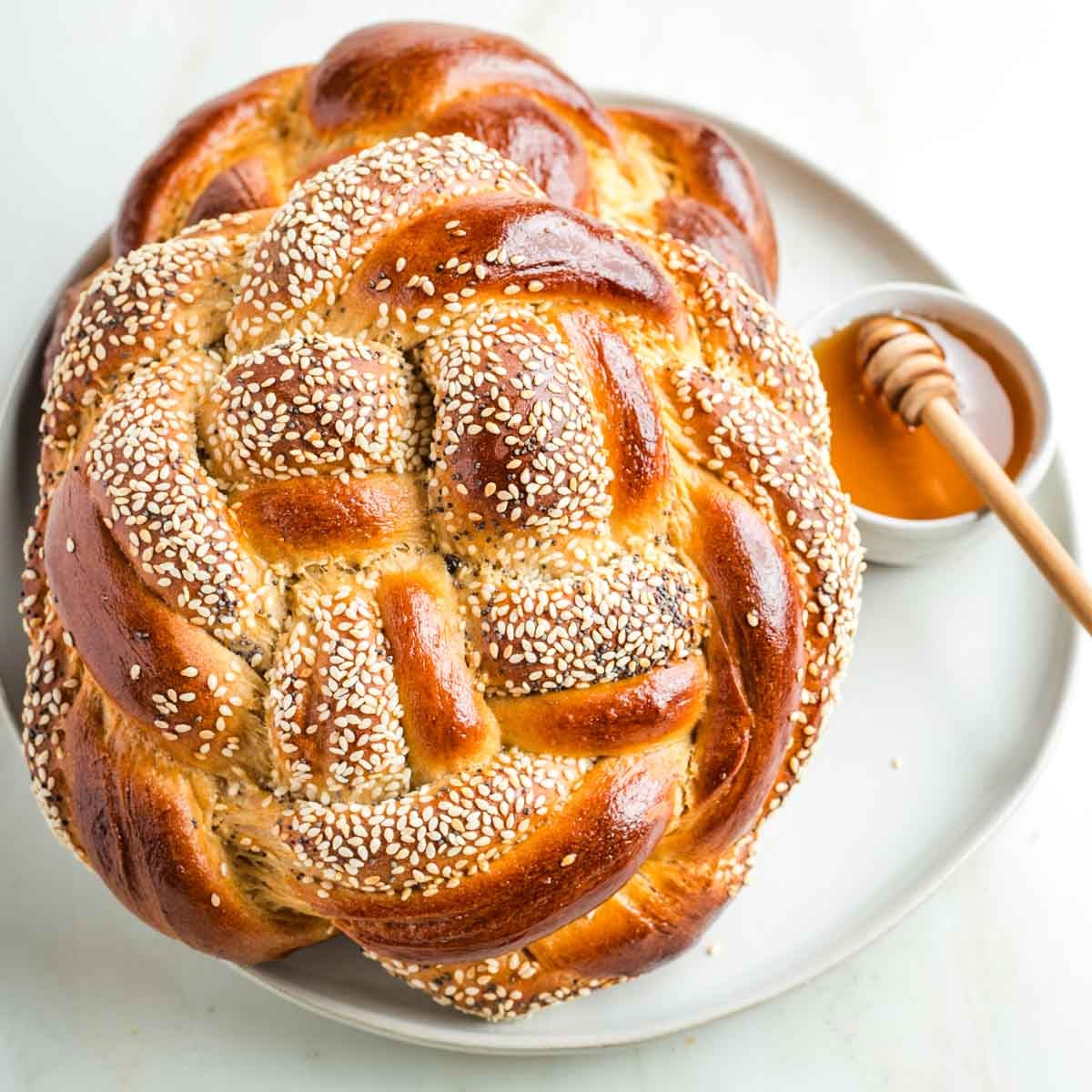 Round, braided challah bread with honey for dipping.
