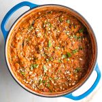 Dutch oven filled with thick and chunky tomato based stew.