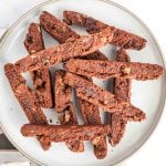 Plate full of chocolate biscotti with chocolate chips and almond slivers.