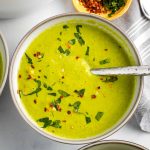 Bright green pureed soup, sprinkled with fresh herbs and crushed red pepper.
