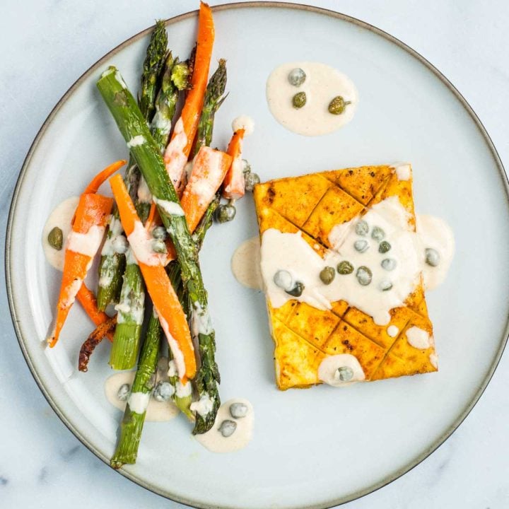 Tofu steak, carrot and asparagus drizzled with tahini lemon caper sauce.