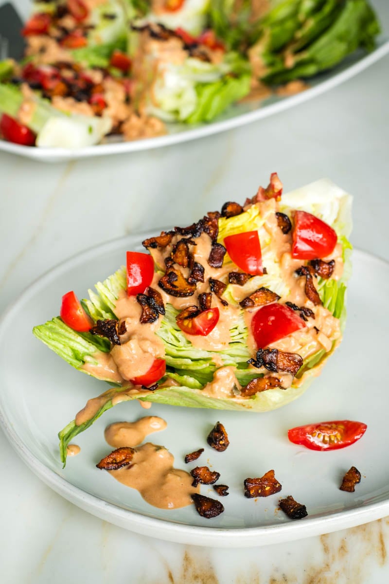 A wedge of iceberg lettuce drizzled with russian dressing plus chopped tomatoes and shiitake bacon crumbles. 