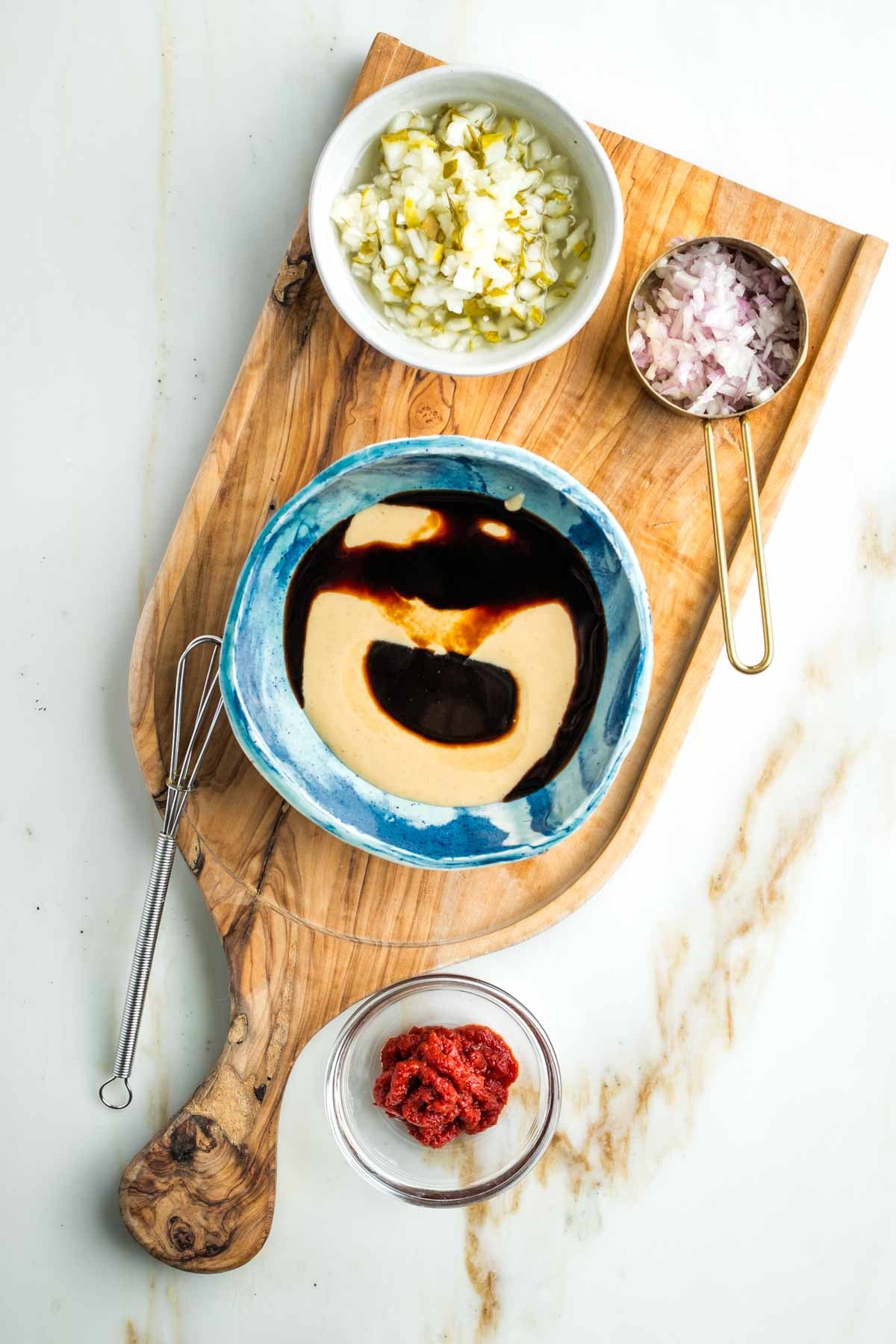 Small bowl with tahini, tamari and maple syrup plus dishes with chopped pickles, minced shallot and tomato paste.