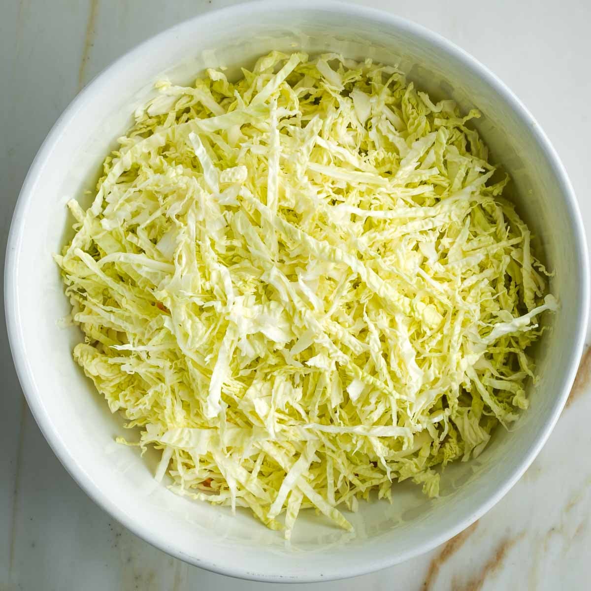 Shredded savoy cabbage in a white bowl.