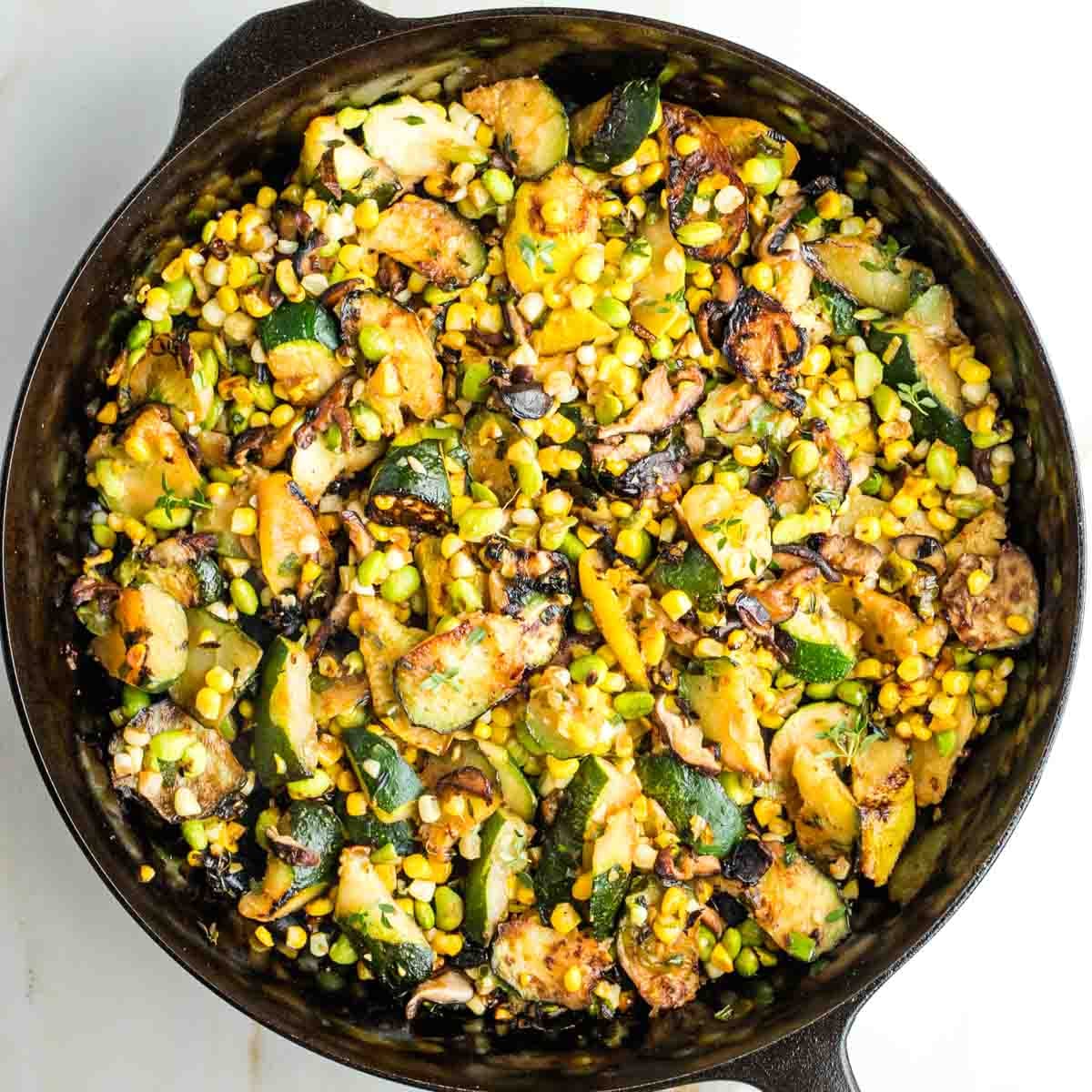 Charred zucchini, mushrooms, corn and edamame in a cast iron skillet.