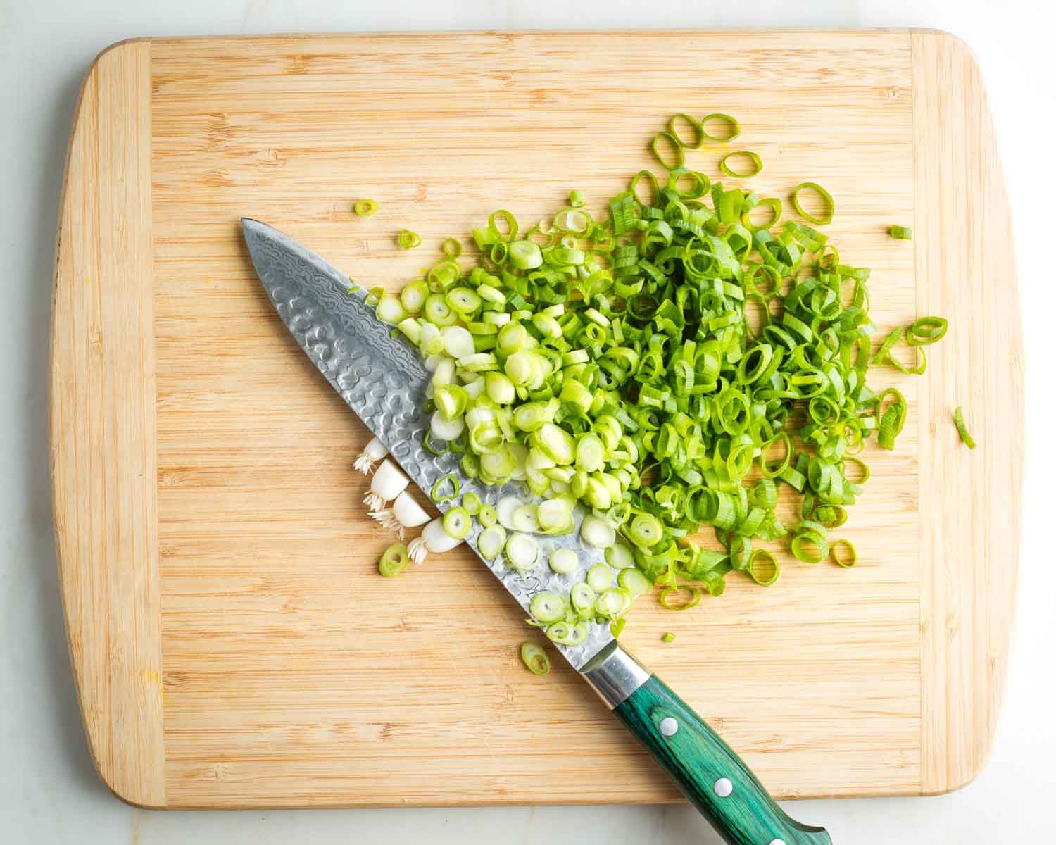 Thinly slicing white and green parts of the scallions.