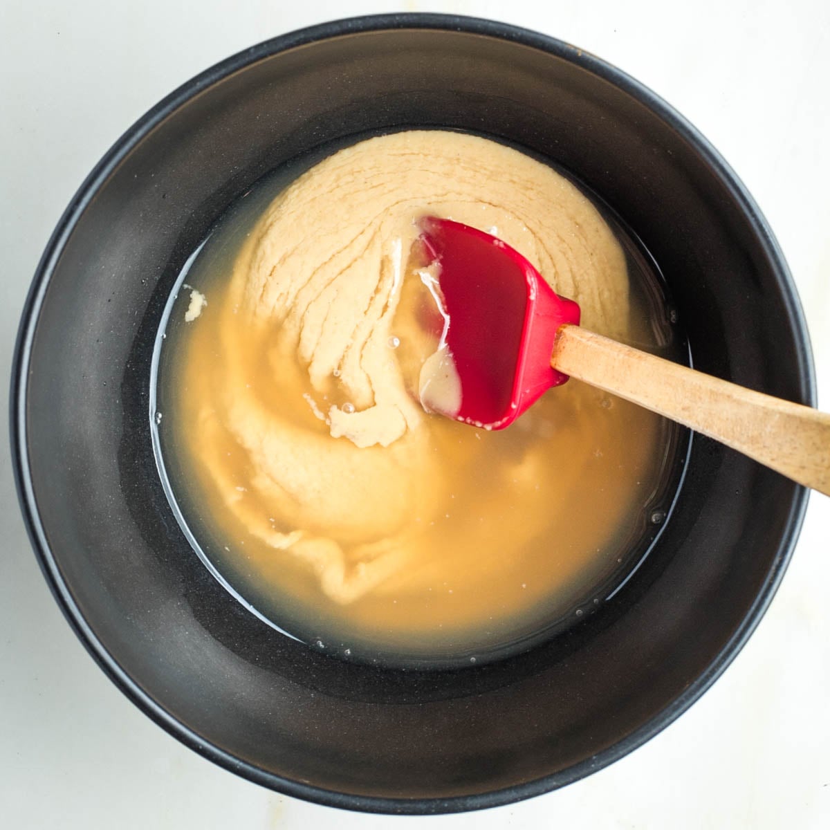 Stirring water and lemon juice into tahini.