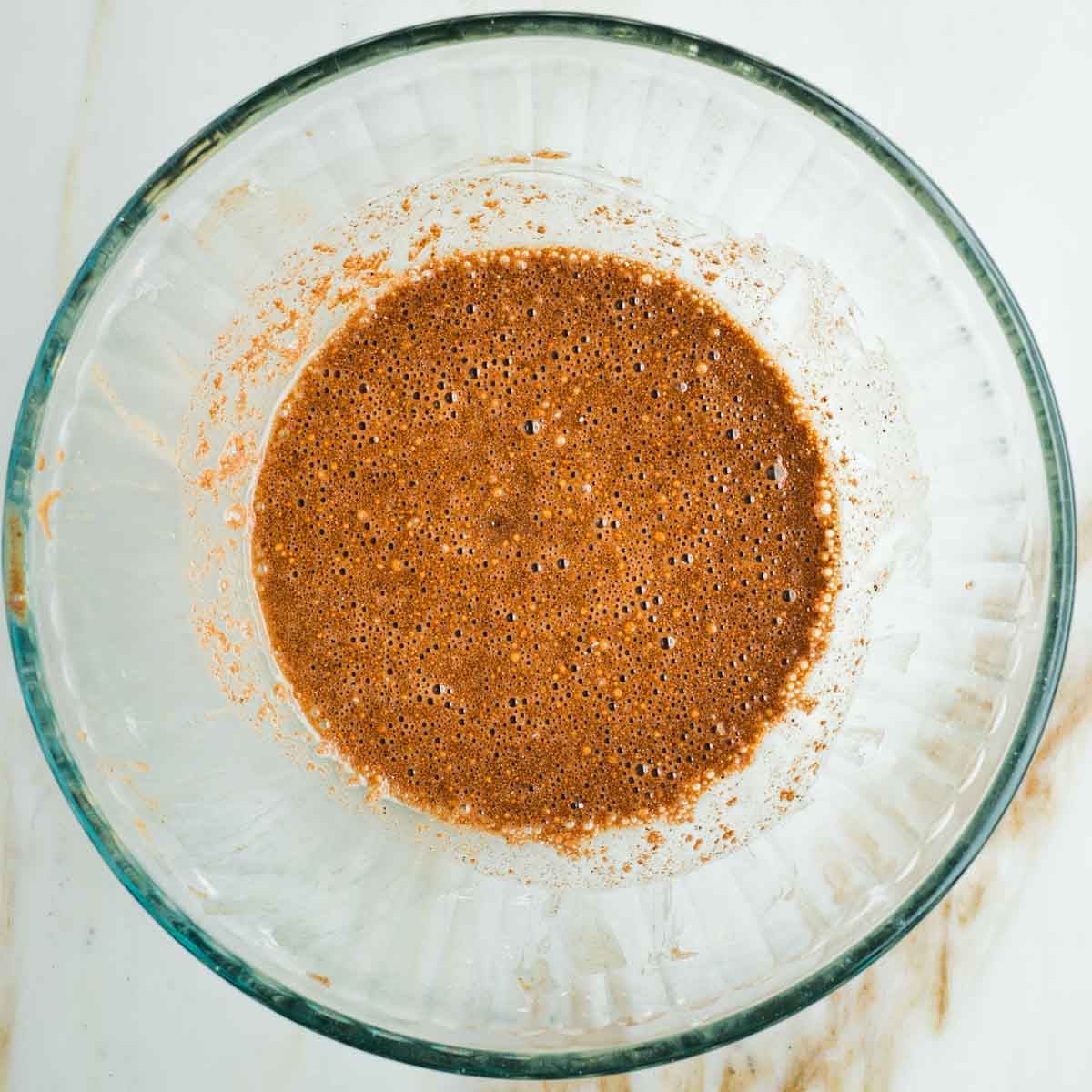 Brown spices combined with maple syrup and lemon juice to create a brown liquid.