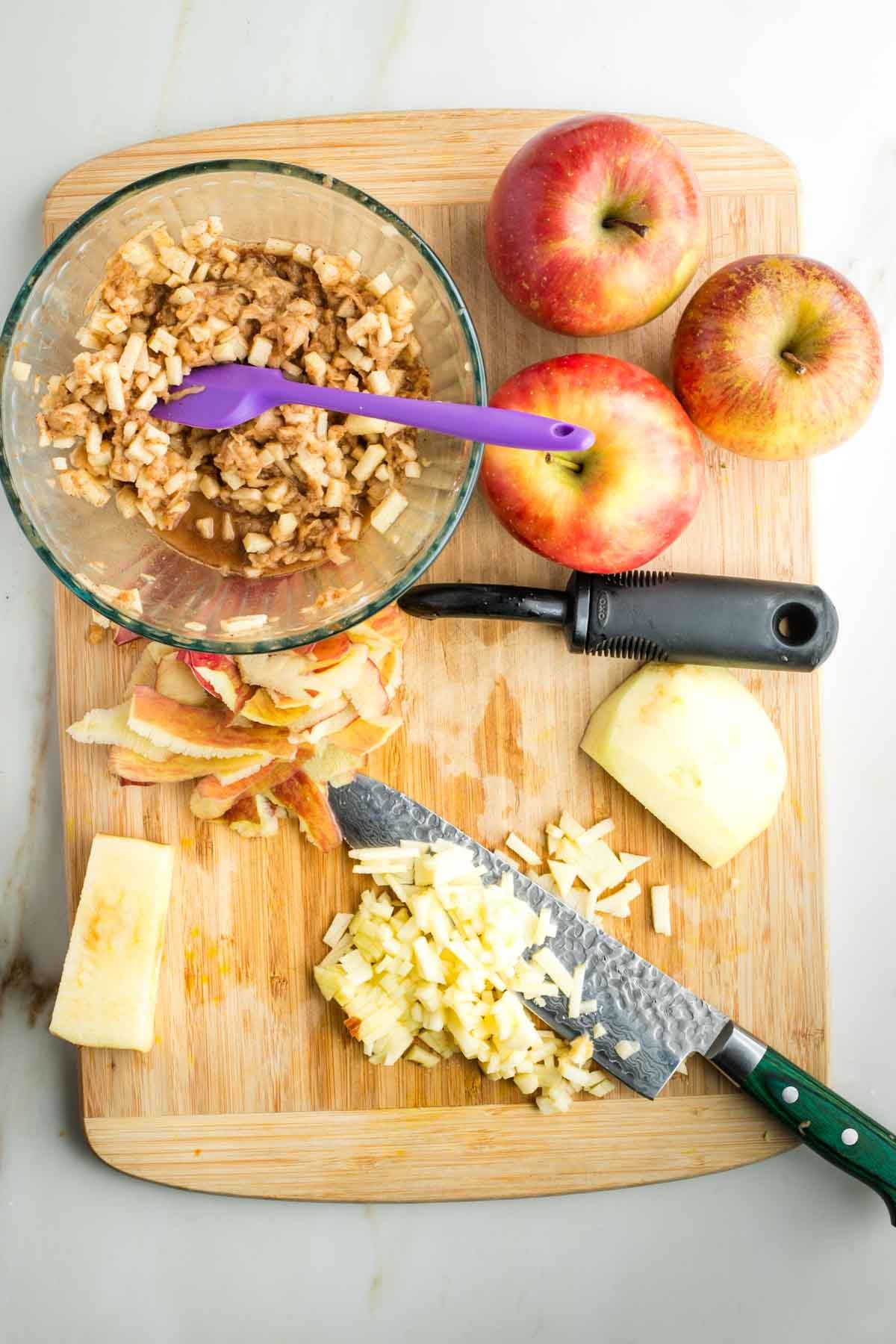 Dicing apples into small pieces and adding them to a bowl with spices in lemon juice.