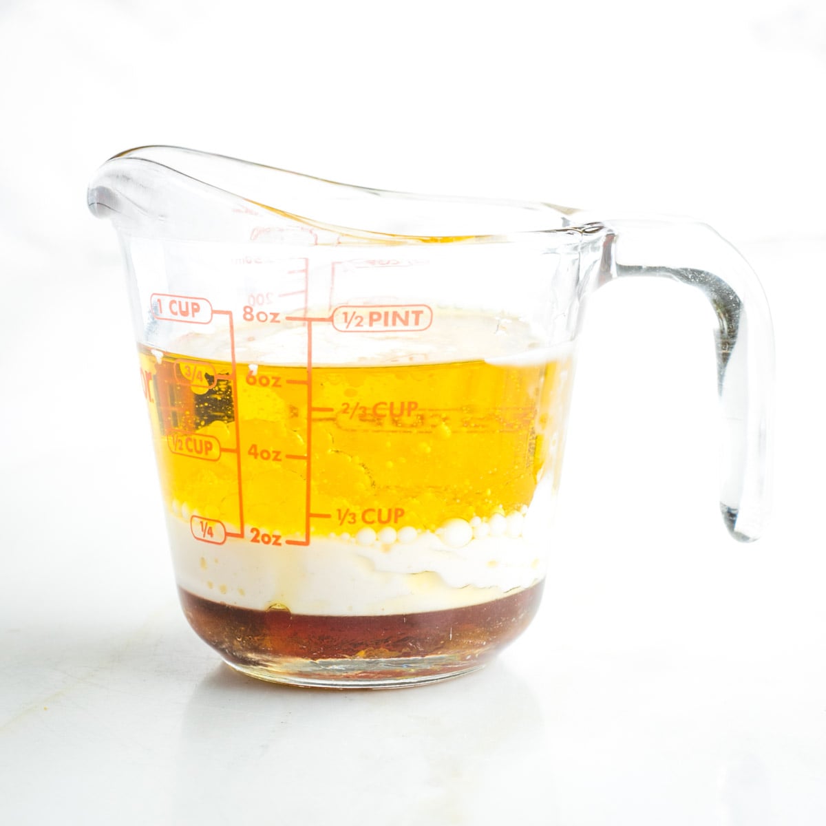 Pyrex measuring cup with olive oil, almond milk and maple syrup.
