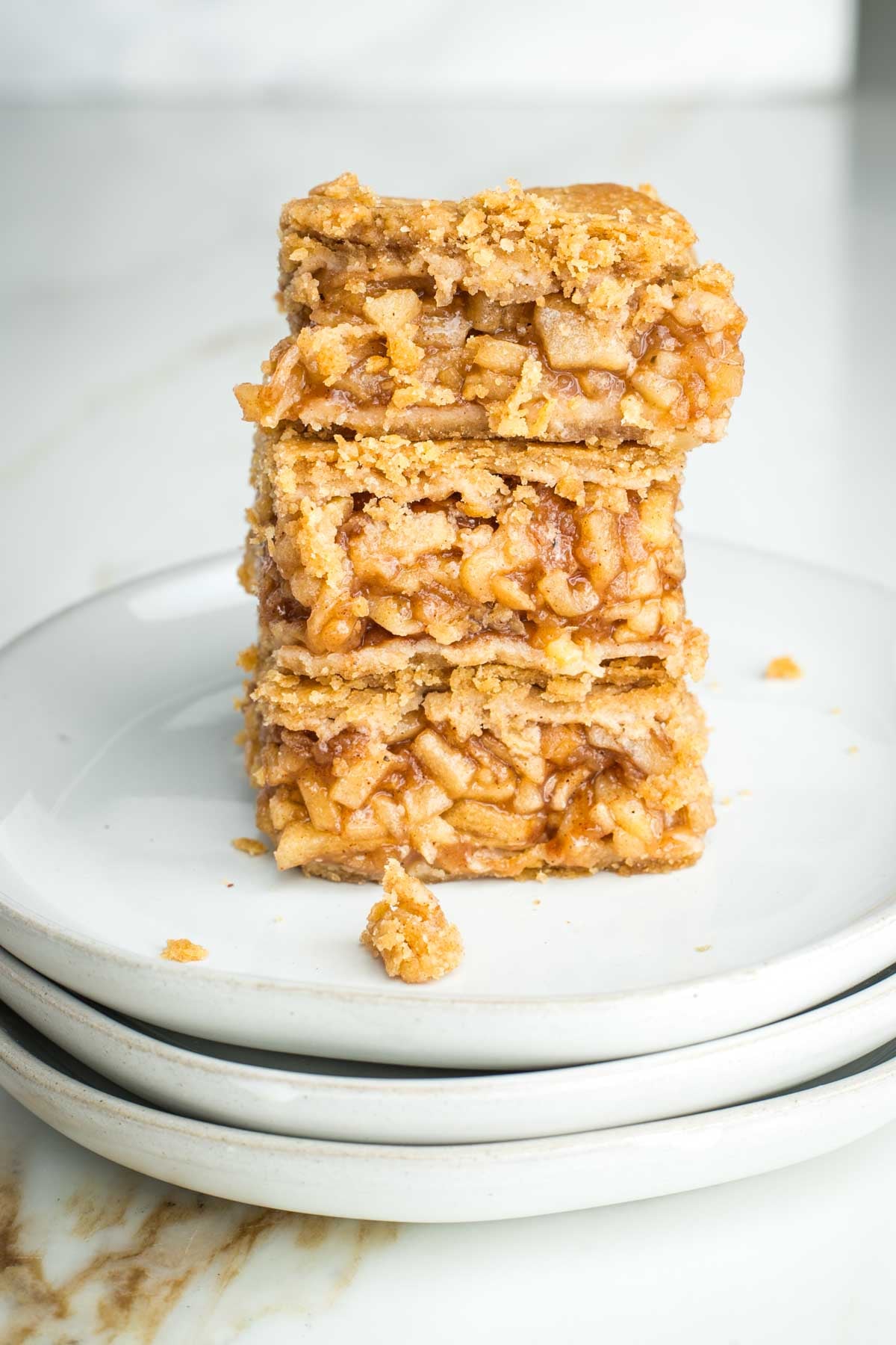 Three apple pie bars stacked on top of each other, showing the filling inside.