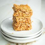 Stack of three apple pie bars with tiny pieces of apples in a thick jammy sauce, nestled between layers of flakey vegan crust.