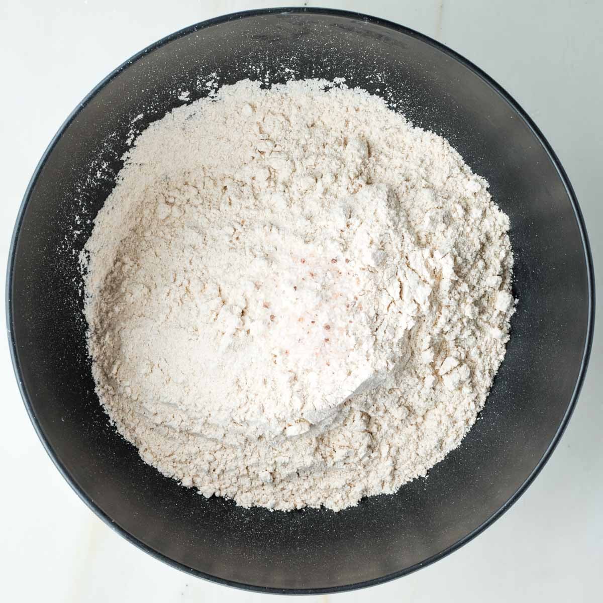 Flour and salt in a black bowl.