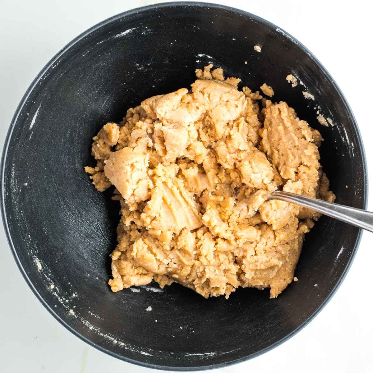 Lumpy pie dough in a black bowl.