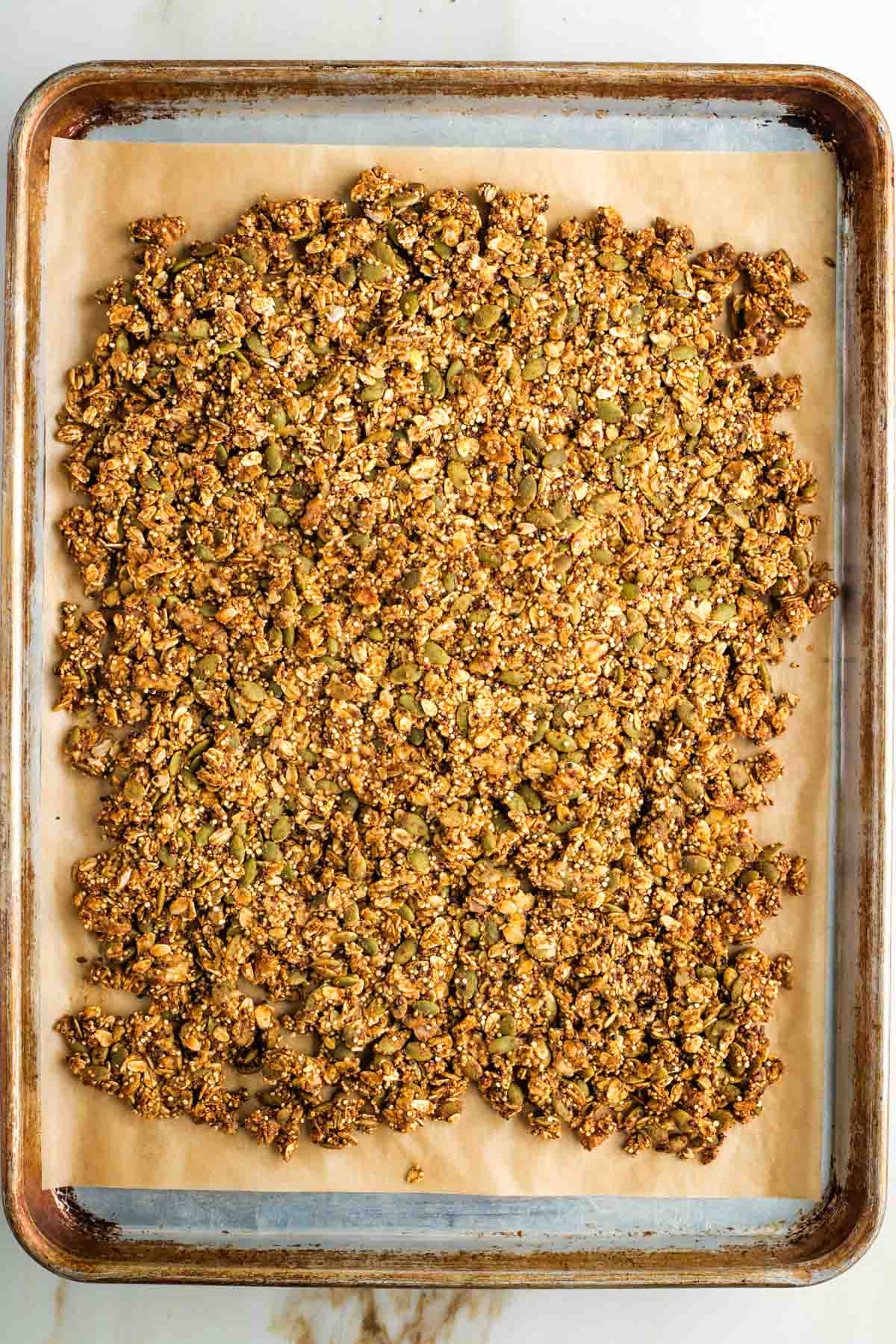 Large rimmed baking sheet filled with golden brown granola.
