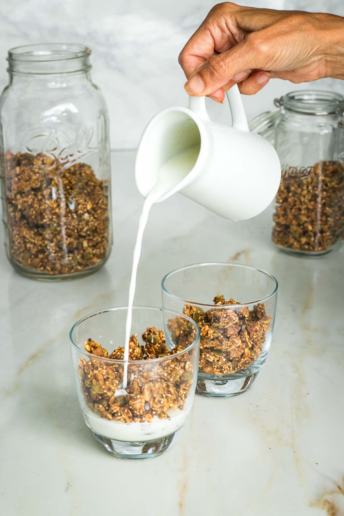 Pouring milk into a glass with granola.