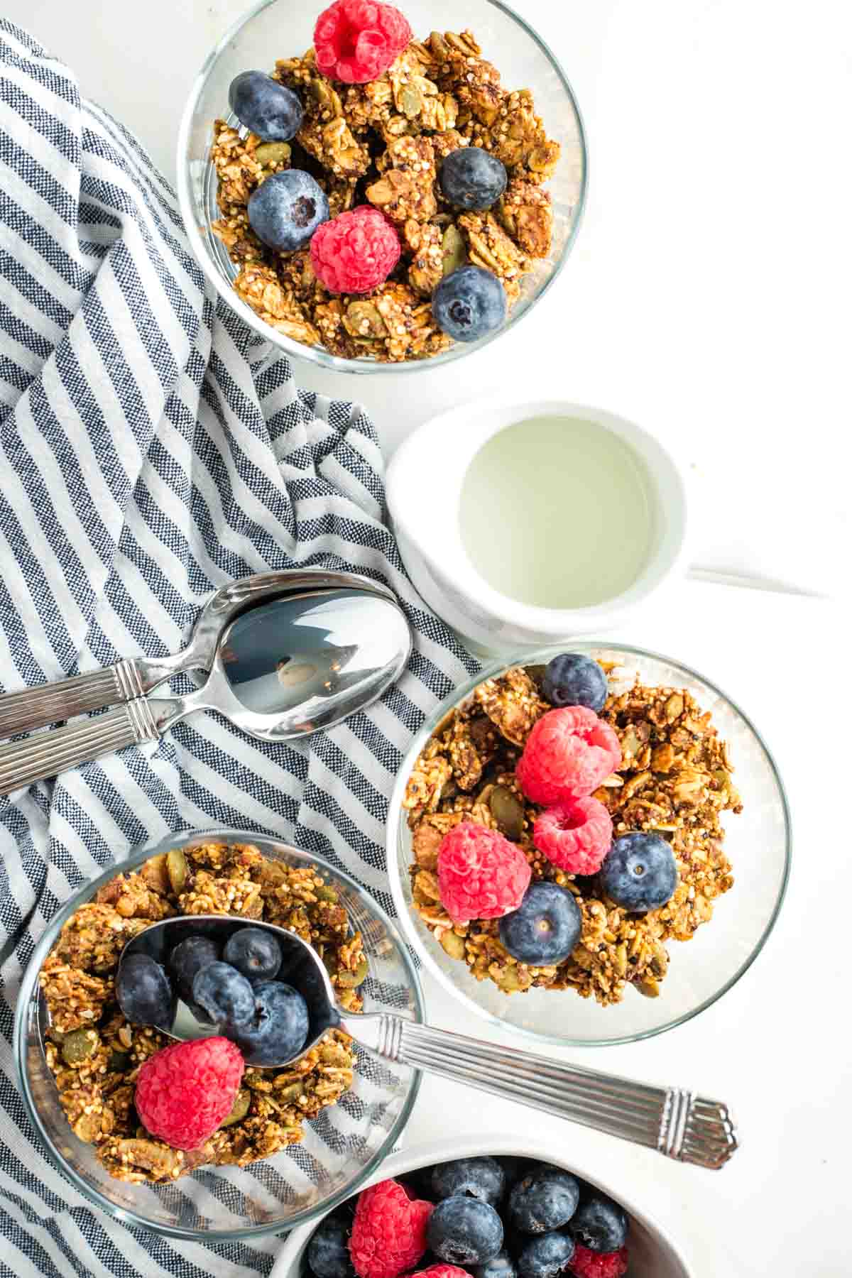 Glasses filled with pumpkin granola and topped with raspberries and blueberries