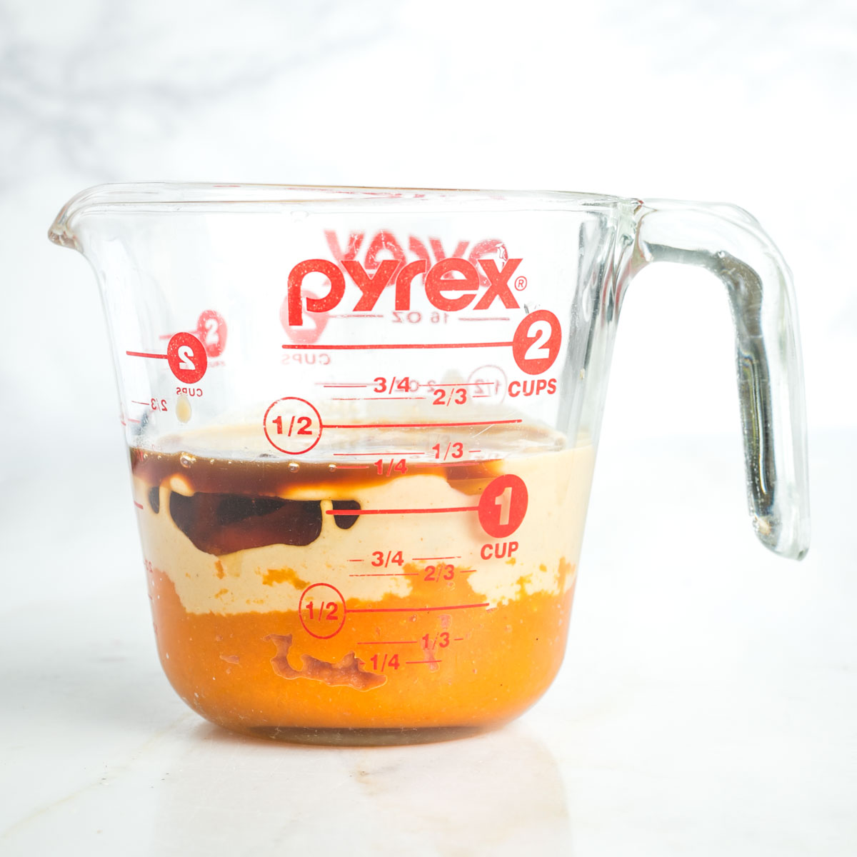 Pyrex measuring cup with layers of pumpkin, maple syrup, tahini and vanilla.