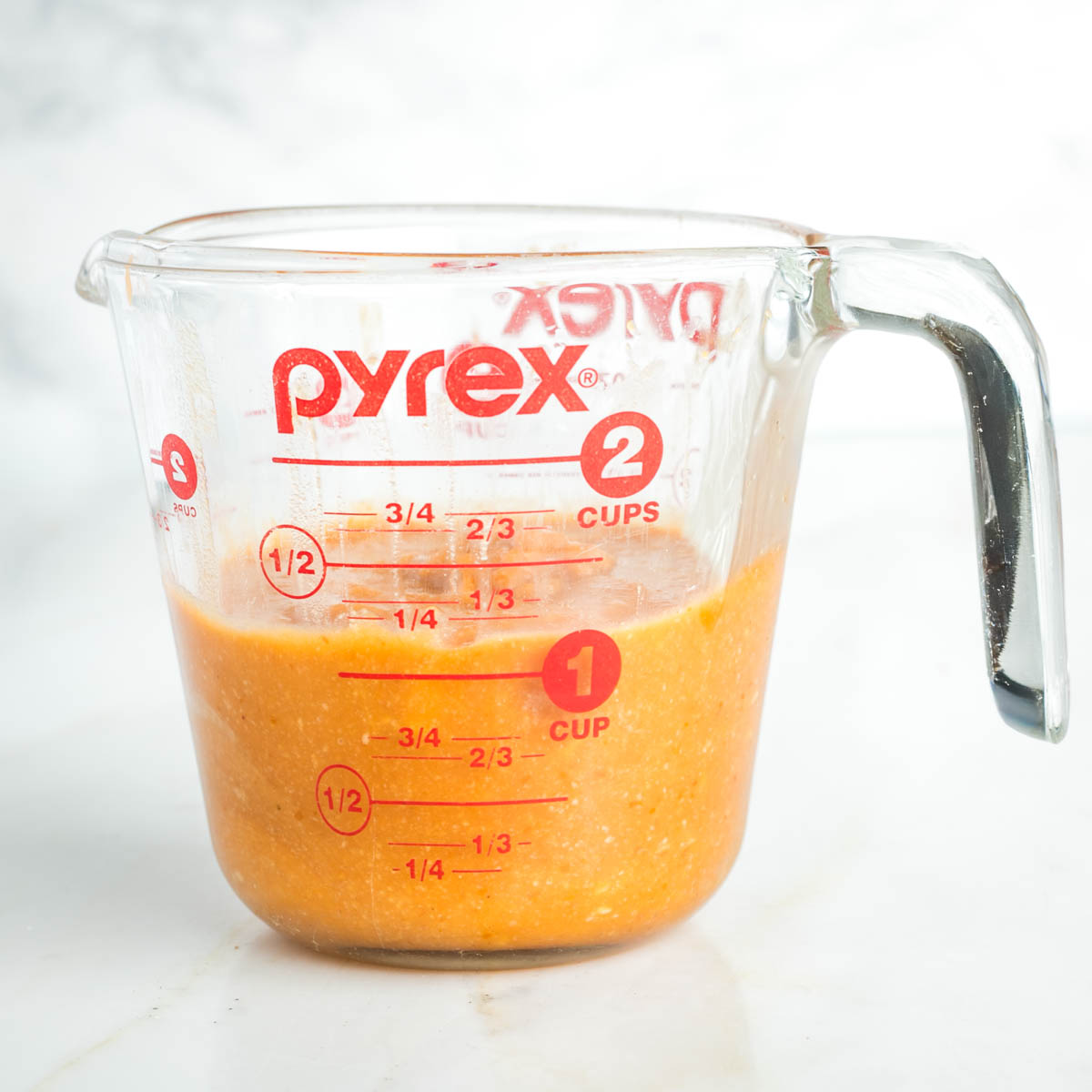 Orange pumpkin mixture in a glass measuring cup.