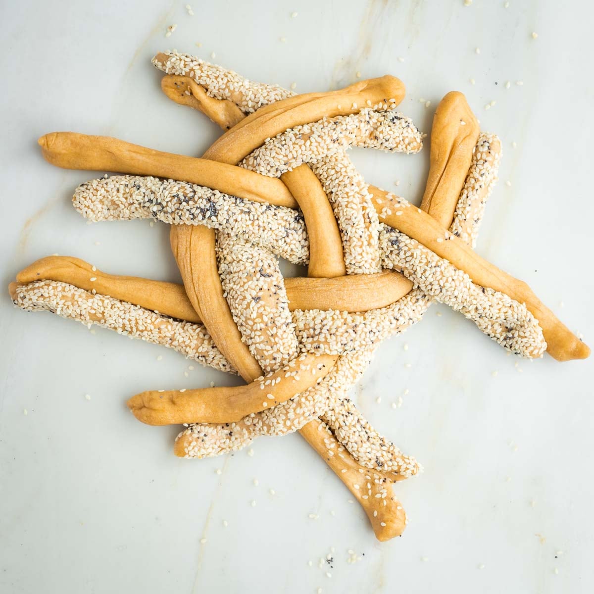 Pairs of seeded or plain strands of dough crossing over in a pattern to form a braided round.