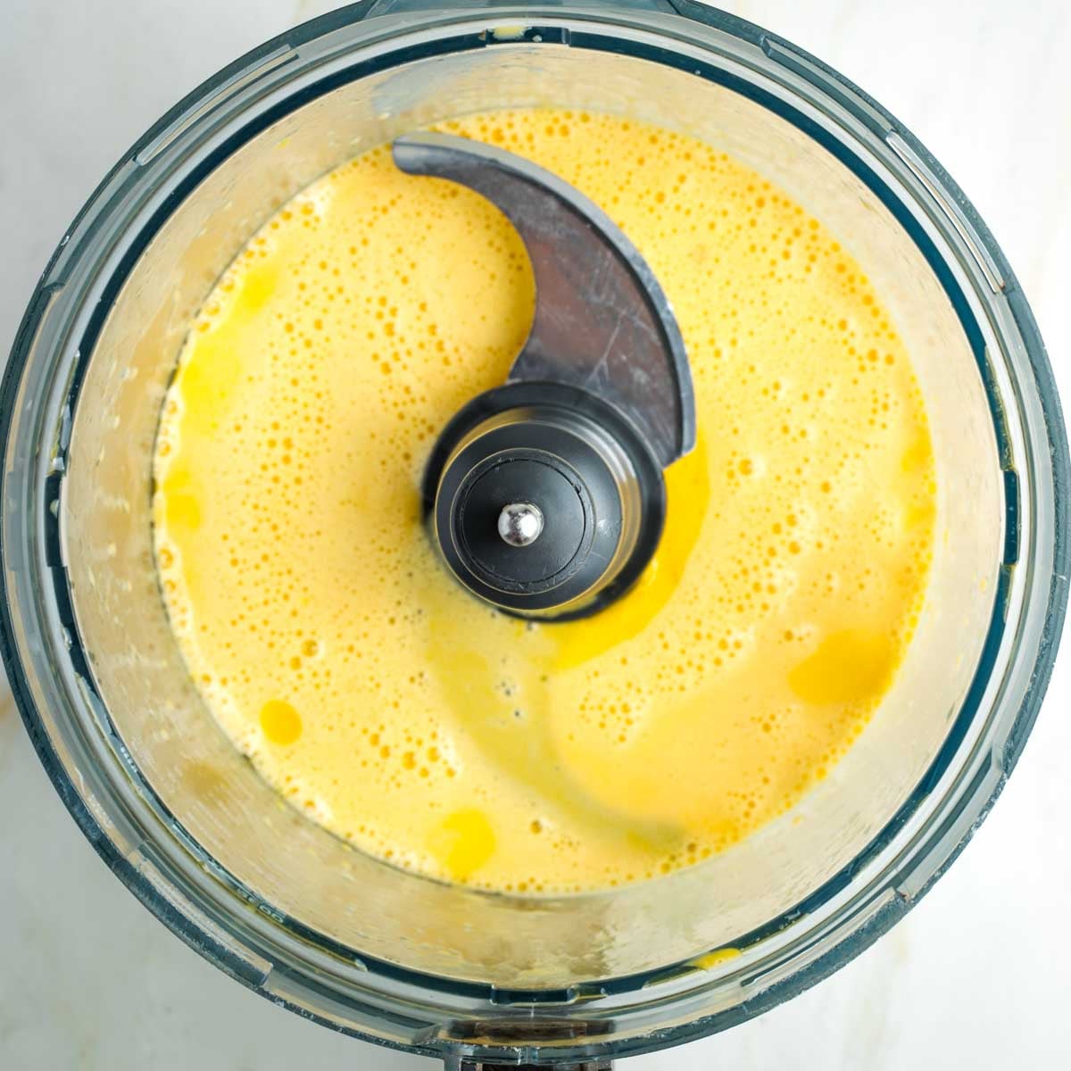 Food processor bowl with whipped eggs and oil.