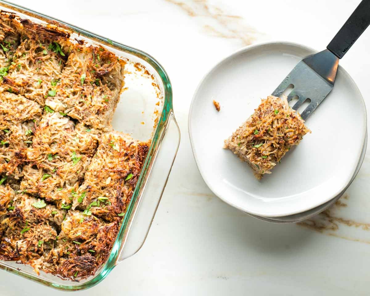 Spatula serving a piece of kugel from the baking dish with a whole batch. 