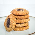 Walnut thumbprint cookies filled with chocolate, in a stack.