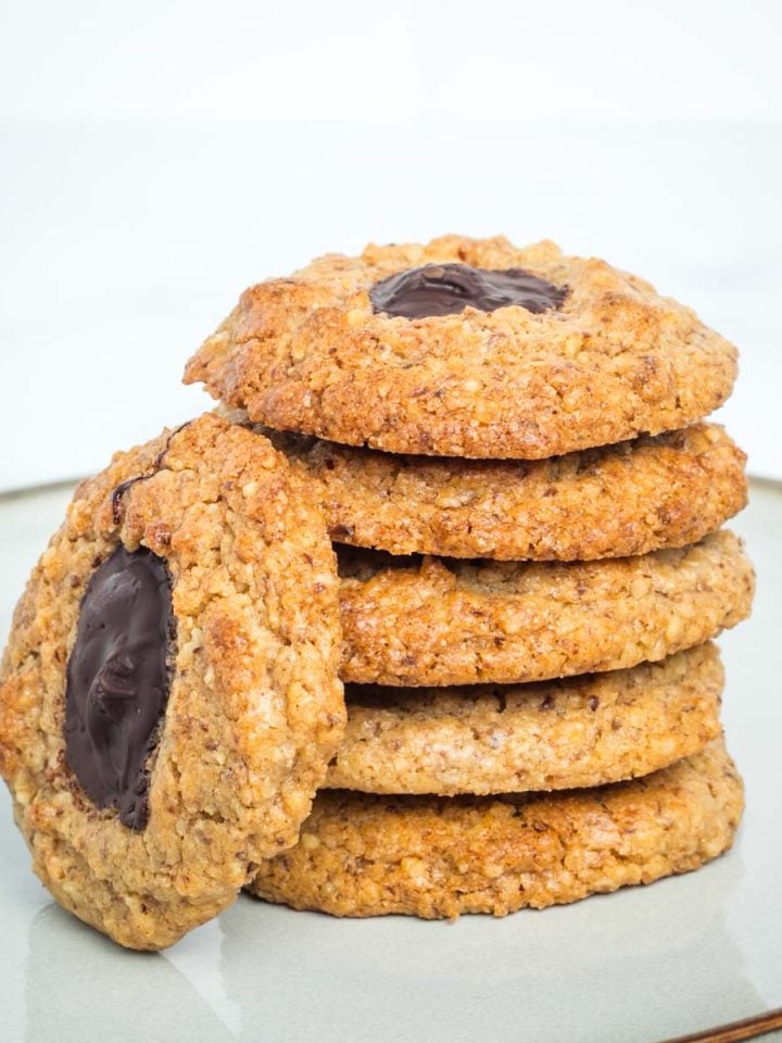 Walnut thumbprint cookies filled with chocolate, in a stack.