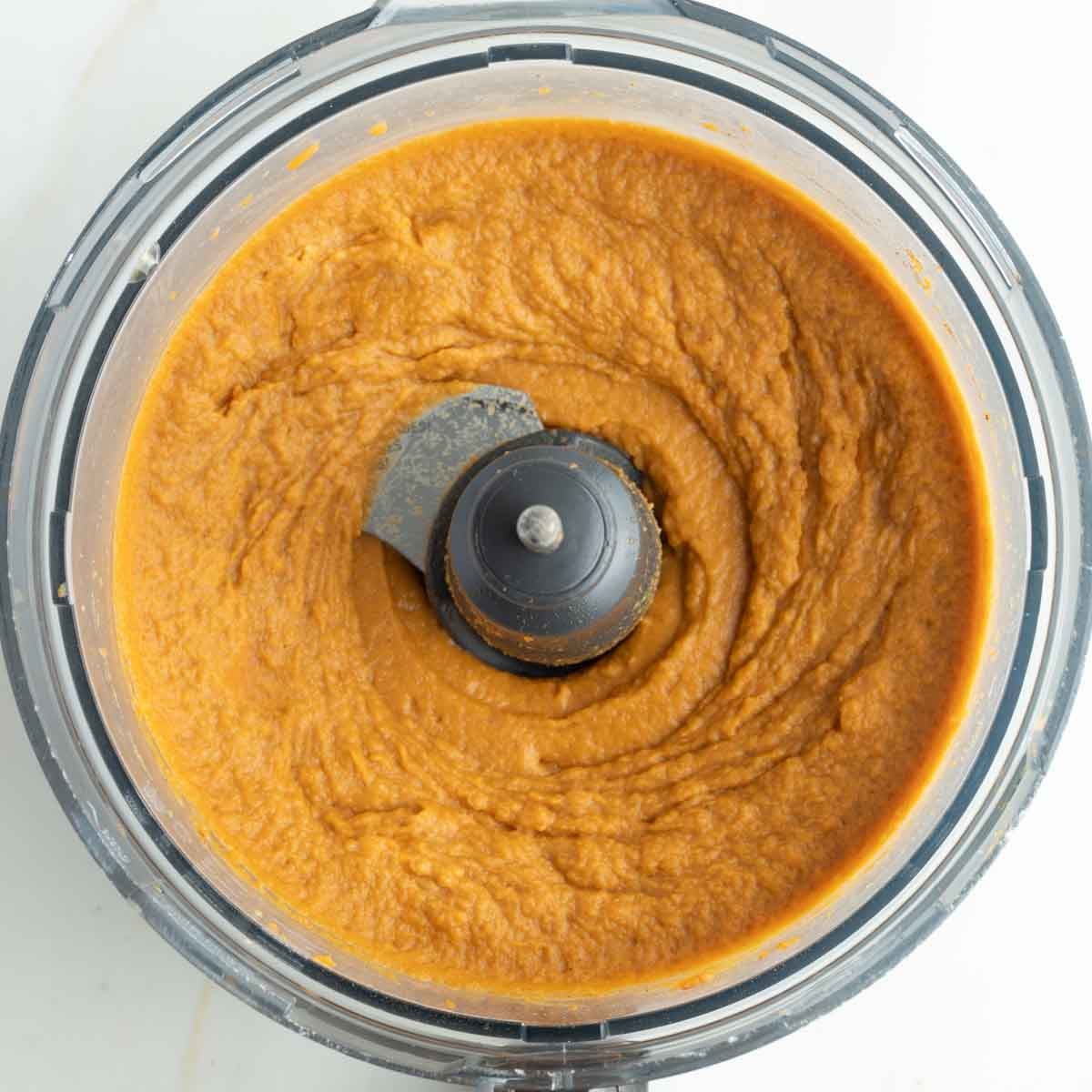Smooth, orange sweet potato mixture in the bowl of a food processor. 