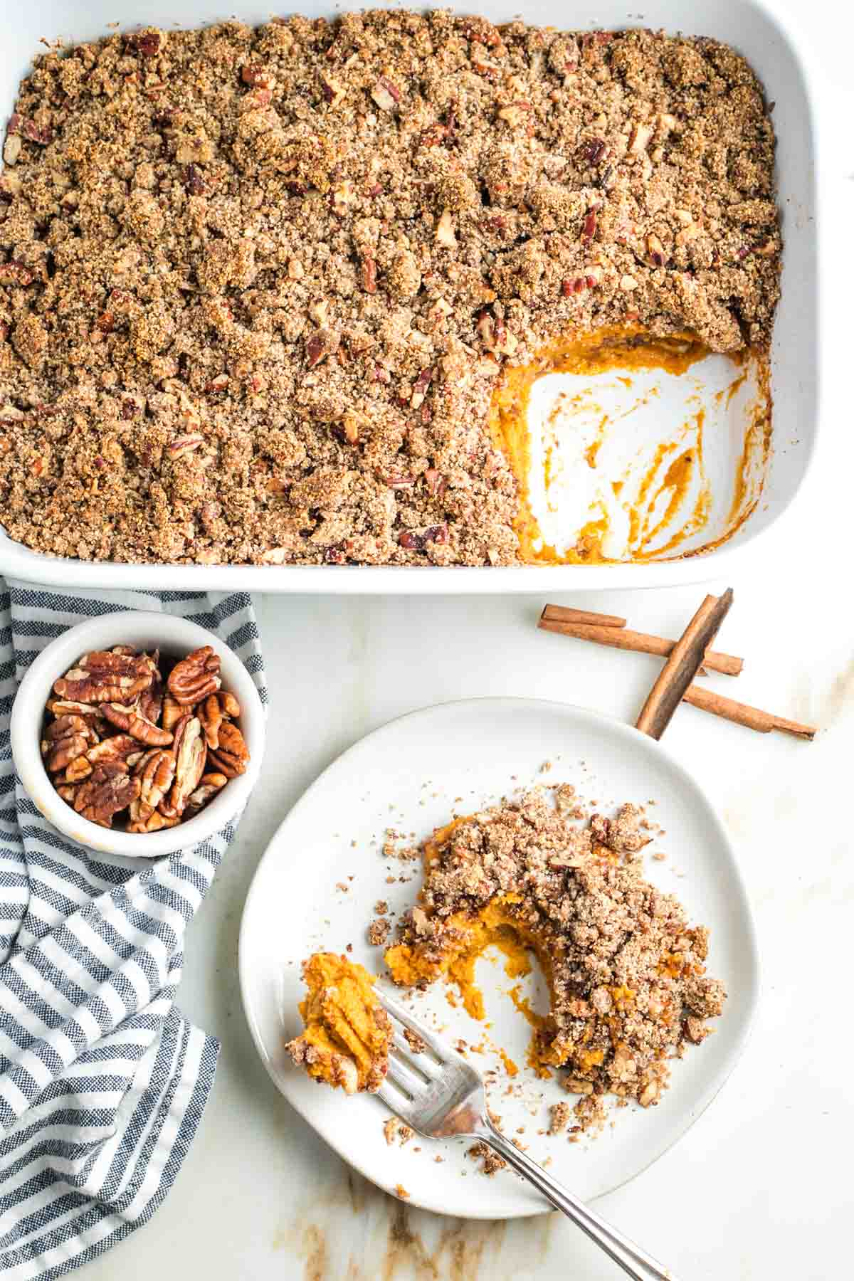 Sweet potato casserole with maple pecan crumble topping, with a serving scooped onto a plate. 
