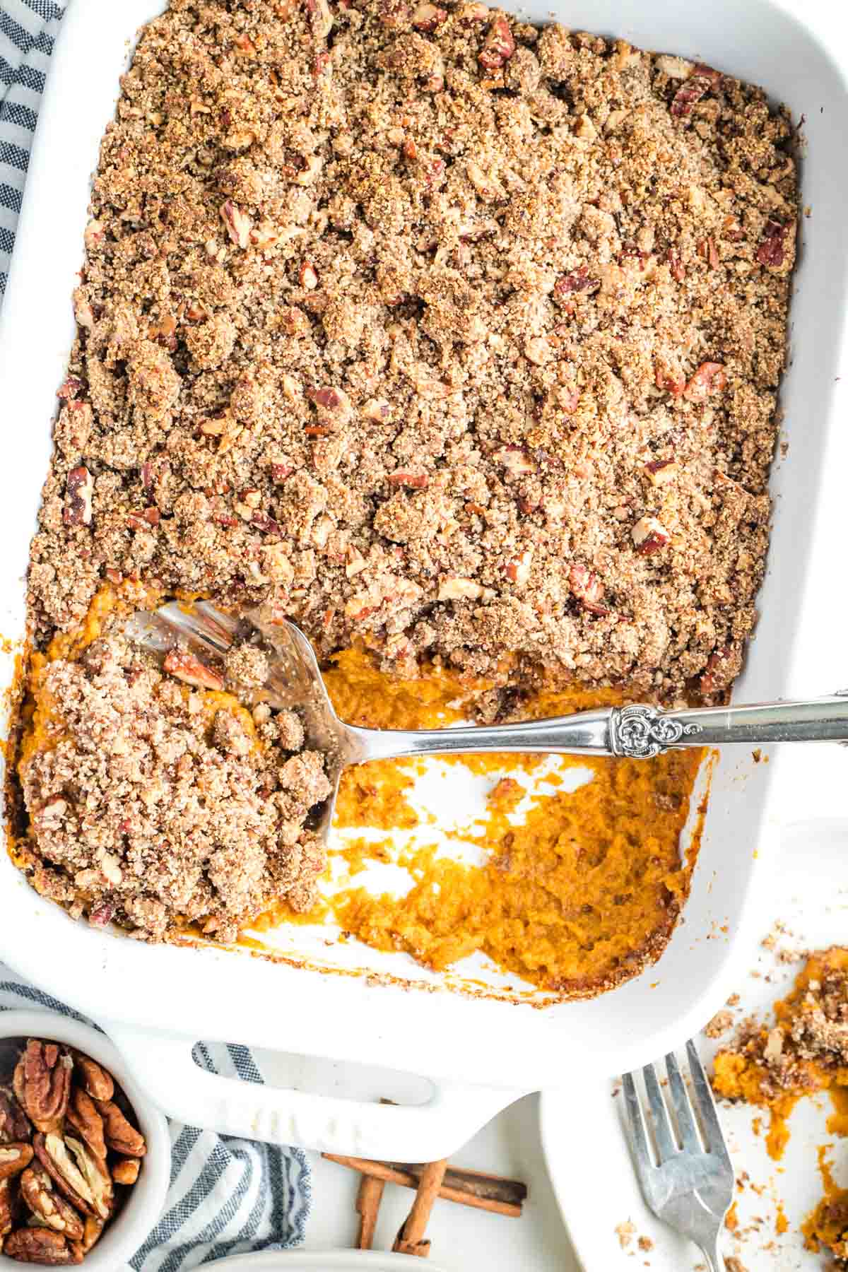 Large serving spoon scooping out some sweet potato casserole with crumbly maple pecan topping. 