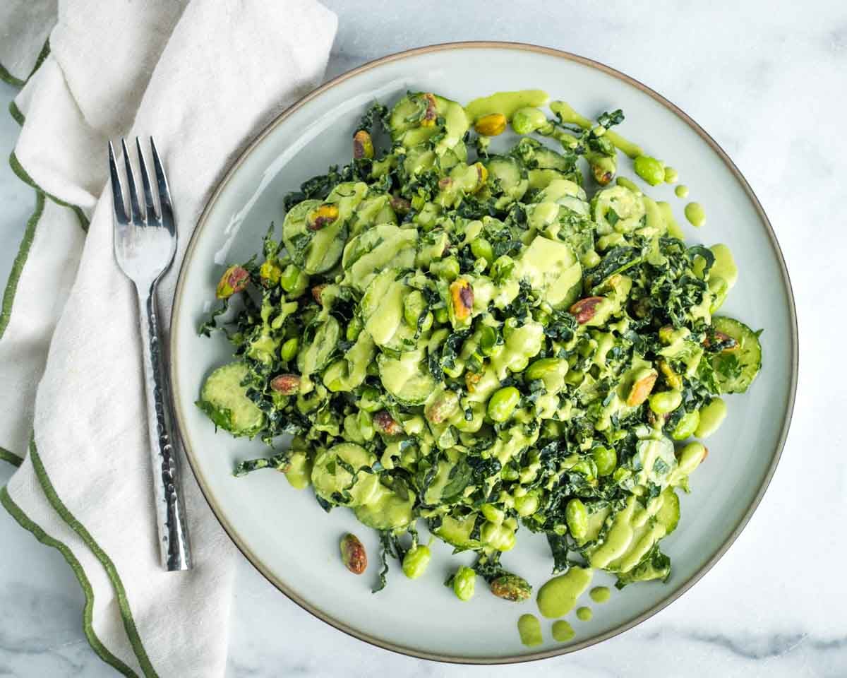 Kale, cucumber, pistachio and edamame salad with creamy light green dressing. 