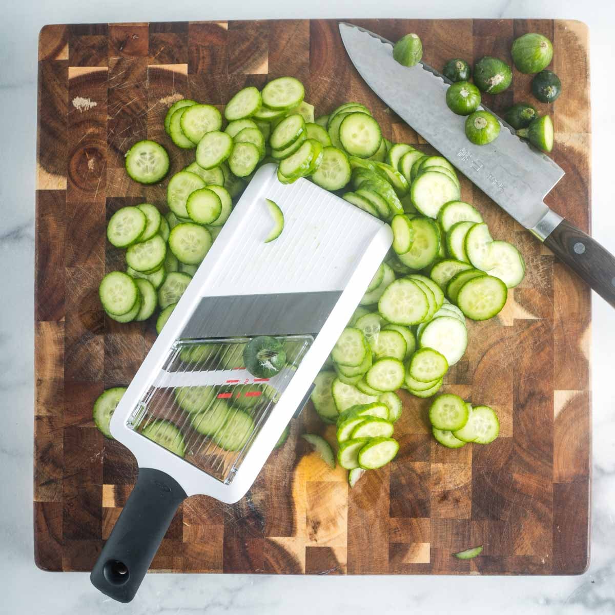 Thinly slicing persian cucumbers on a handheld mandolin.