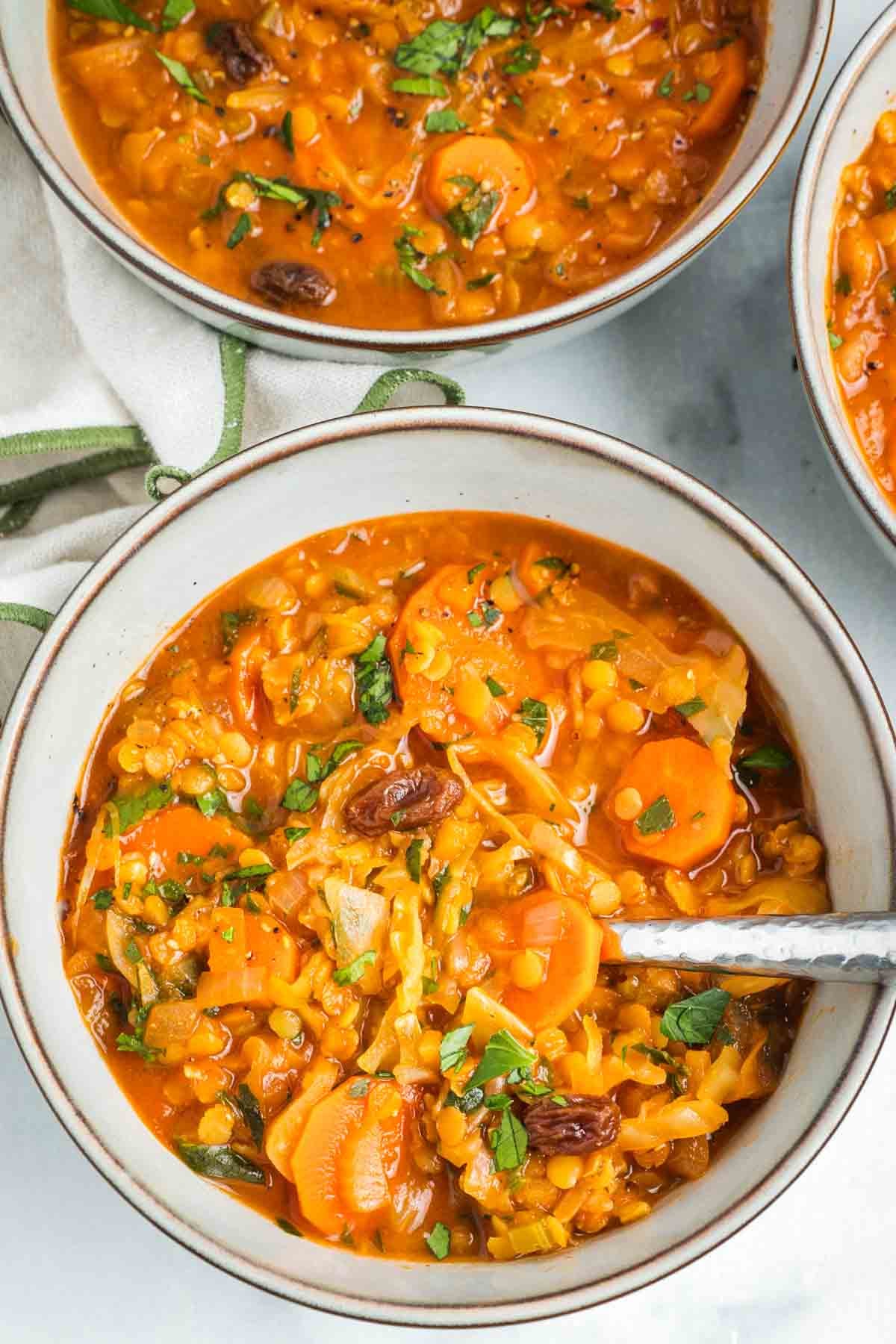 Brothy tomato base for chunky veggie soup with red lentils, raisins and fresh parsley.