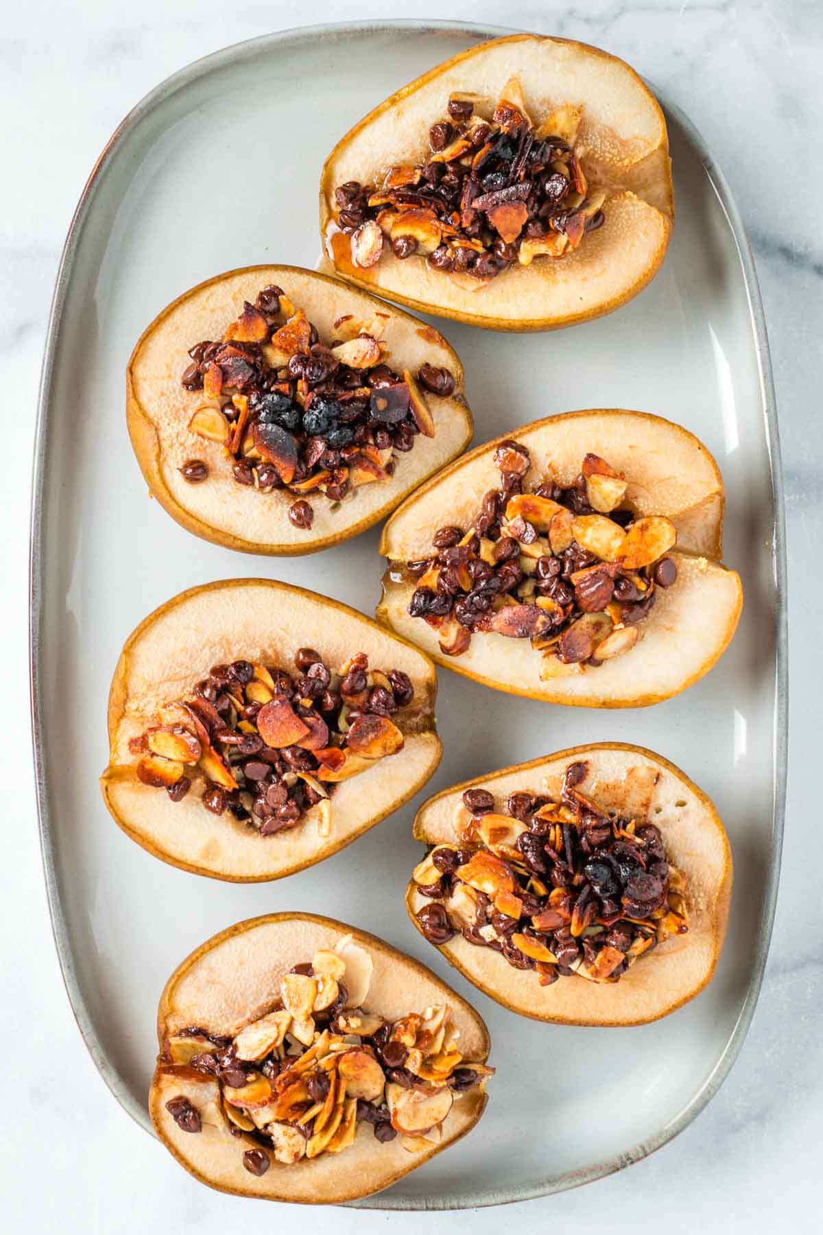 Platter with baked, stuffed pears with melty chocolate and almond mixture. 
