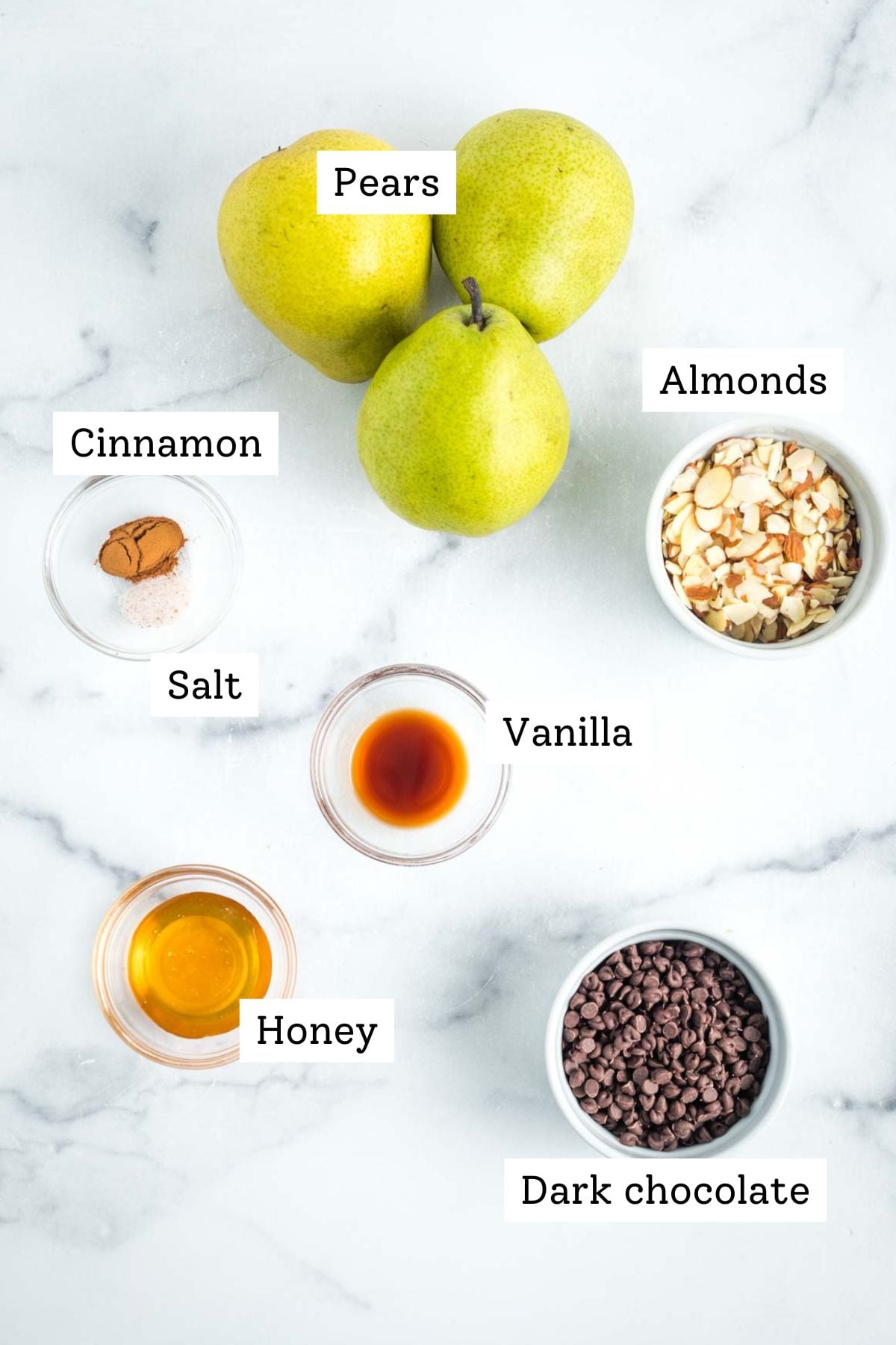 Labeled ingredients for baked pears: pears, cinnamon, salt, vanilla, honey, chocolate, almonds.